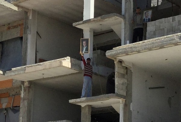 A Homs, sur les lieux de l'attentat , un ouvrier brandit un portrait de Bachar el-Assad